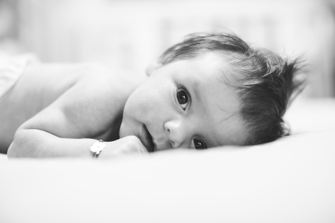 Young baby boy lying in the bed, looking at the camera.